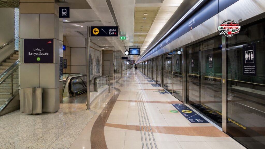 Interior view of Baniyas Square Metro Station Dubai showing the modern underground concourse, platform entrance, digital information displays, escalators, and passengers on the Green Line.