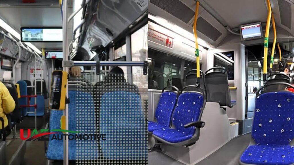 Interior view of a Dubai RTA bus showing blue passenger seats, yellow grab poles, digital stop display screens, and a Nol card validator near the entrance.